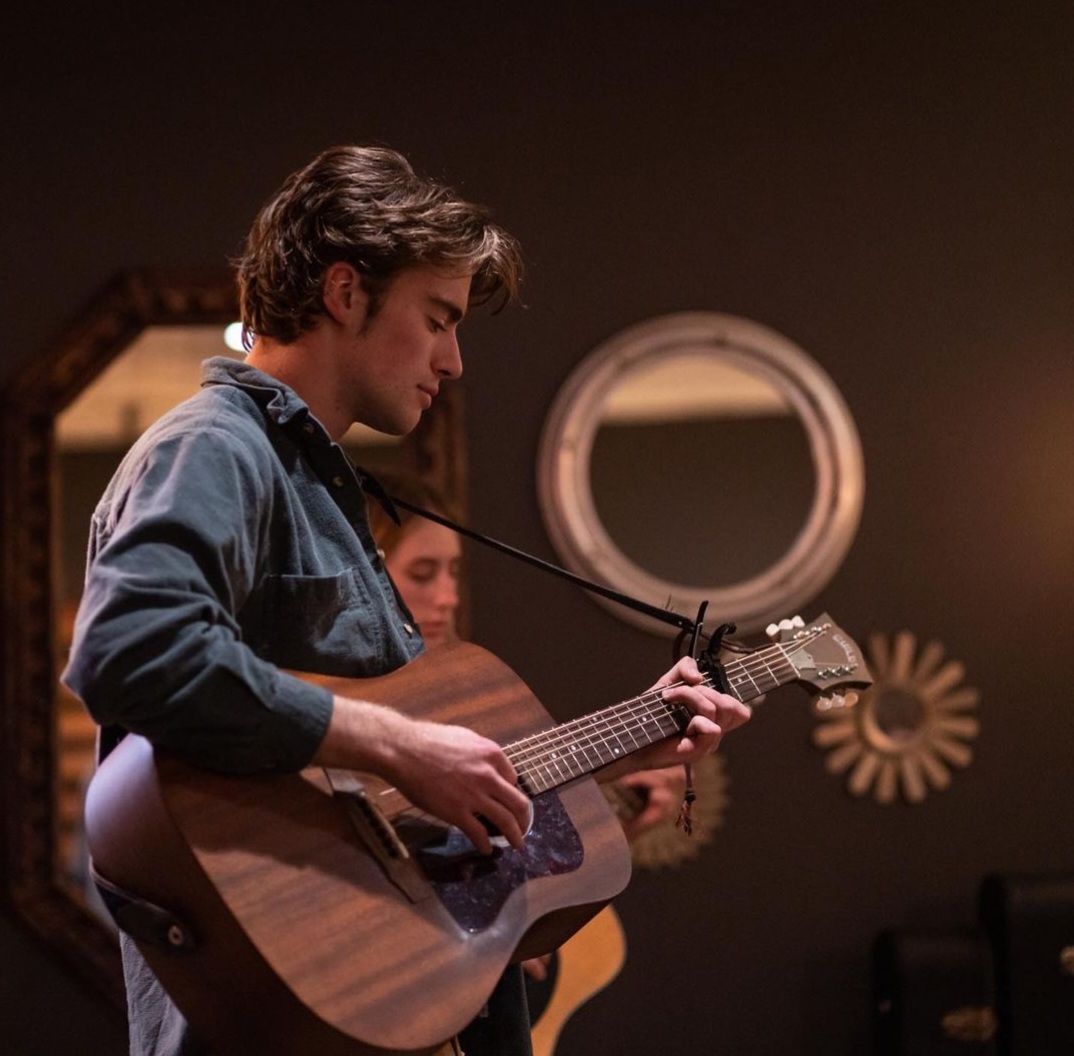 Jack Ooster playing acoustic guitar during an indoor performance