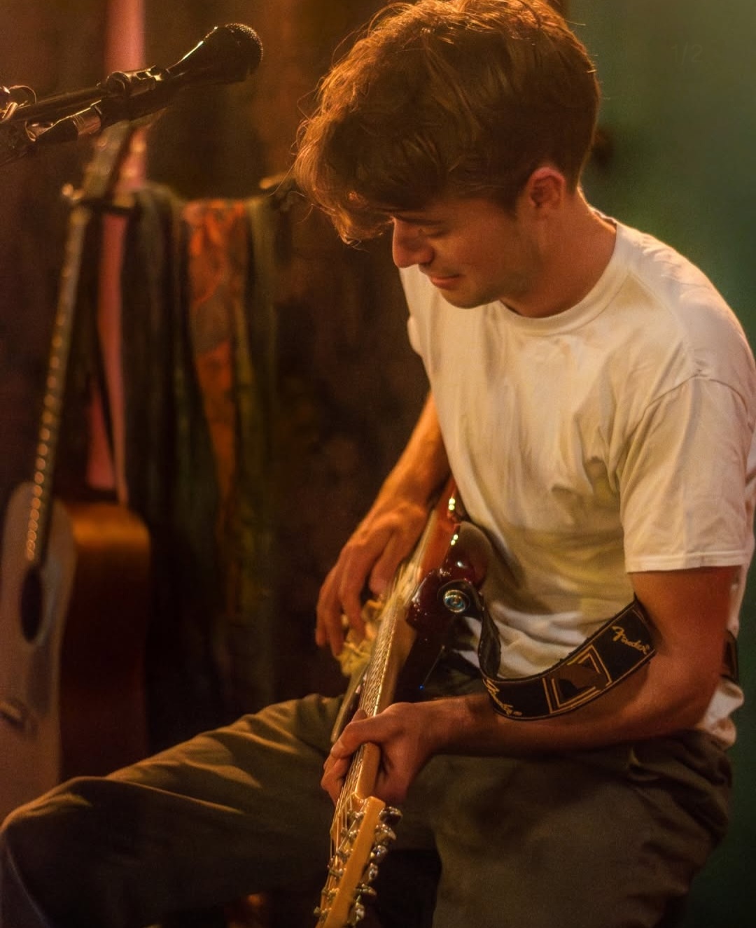 Jack Ooster playing electric guitar under warm stage lighting