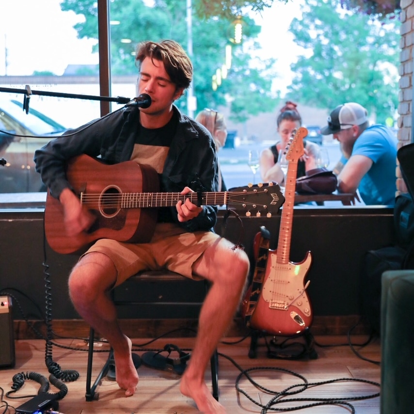 Jack Ooster seated and singing with an acoustic guitar
