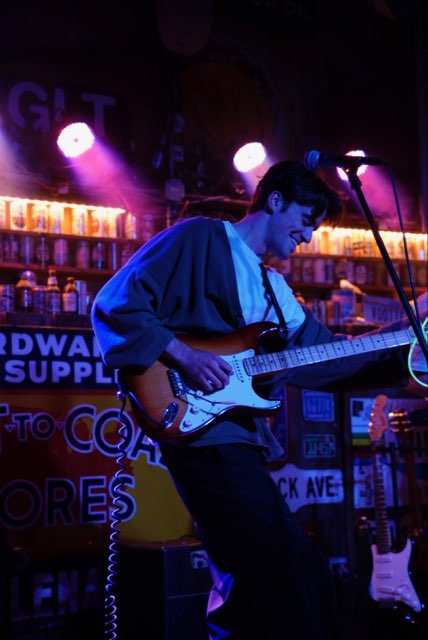Jack Ooster playing electric guitar under blue stage lights